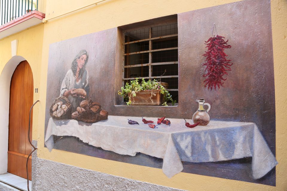 Murales di una donna con alimenti tradizionali calabresi (pane, peperoncino e olio)